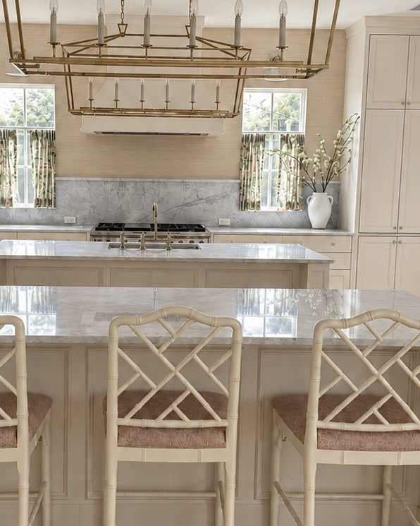 Kitchen with brass lantern, marble islands and bamboo-style counter stools, designed by Emily Hoopes